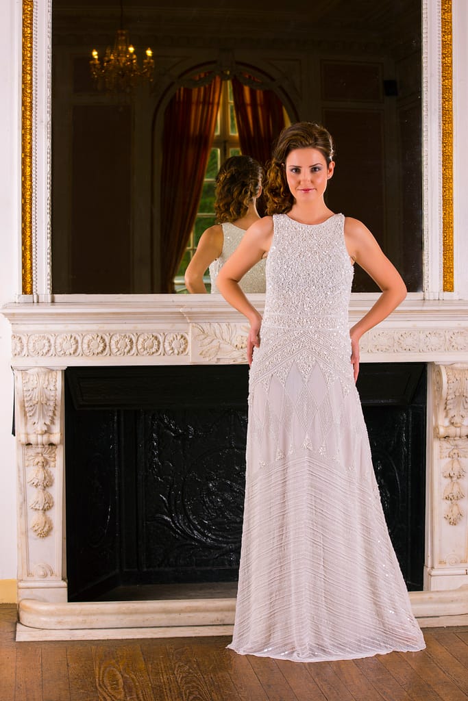 young lady in a cream dress by a fireplace